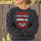 Woman wearing the dark heather Protected By A Smokin' Hot Veteran Sweatshirt outdoors