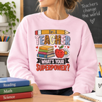 Woman wearing the light pink I'm A Teacher What's Your Superpower Sweatshirt by a chalkboard