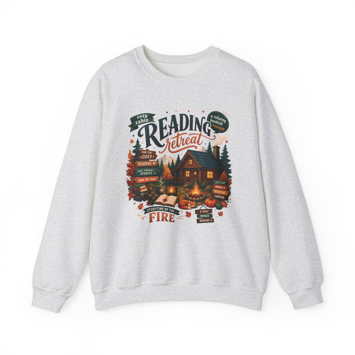 Ash Cozy Cabin Reading Retreat sweatshirt with a glowing log cabin in the pines, stacks of books and a crackling fire, front view