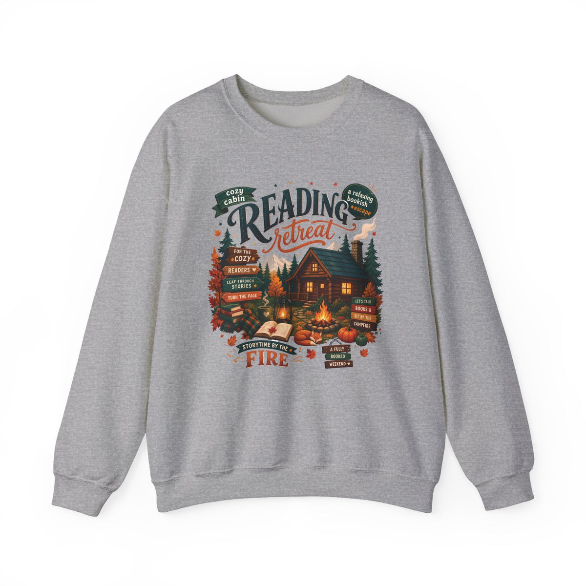 Sport Grey Cozy Cabin Reading Retreat sweatshirt with a glowing log cabin in the pines, stacks of books and a crackling fire, front view