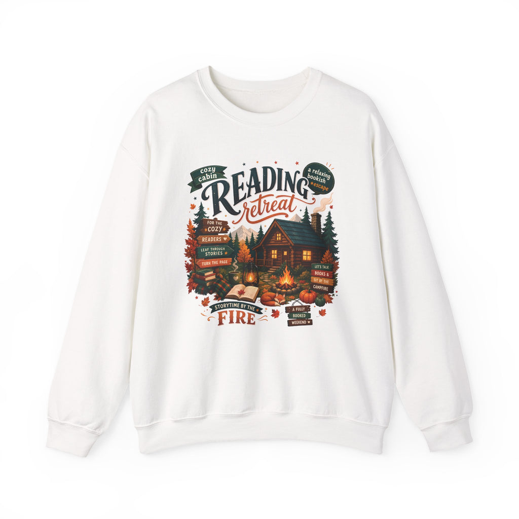 White Cozy Cabin Reading Retreat sweatshirt with a glowing log cabin in the pines, stacks of books and a crackling fire, front view
