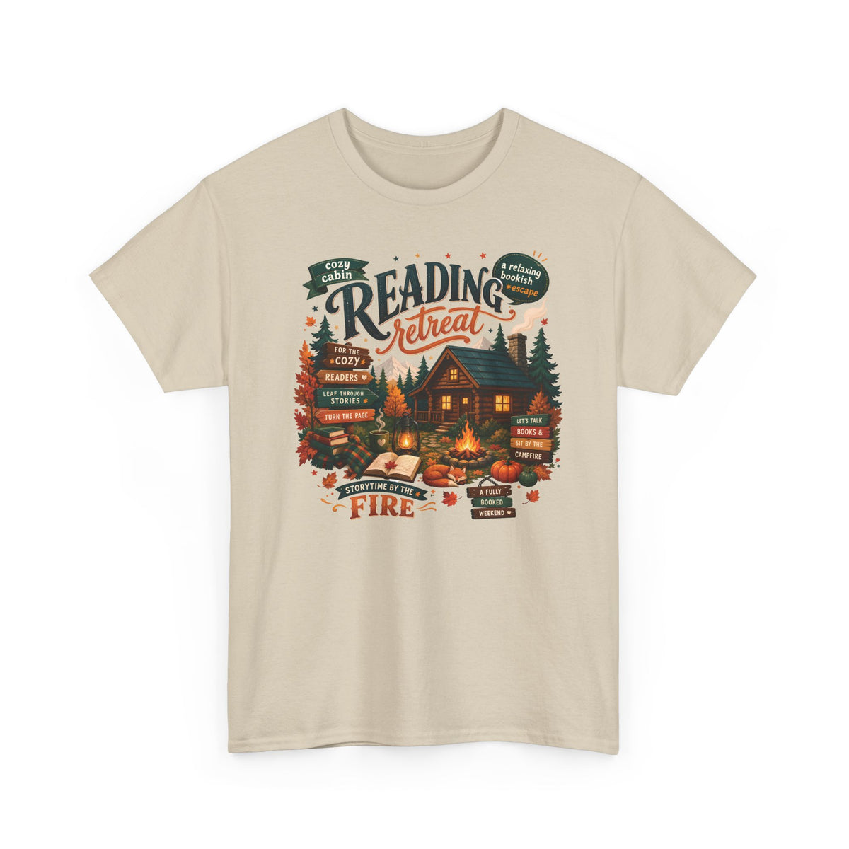 Sand Cozy Cabin Reading Retreat t-shirt with a glowing log cabin in the pines, stacks of books and a crackling fire, front view