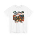White Cozy Cabin Reading Retreat t-shirt with a glowing log cabin in the pines, stacks of books and a crackling fire, front view