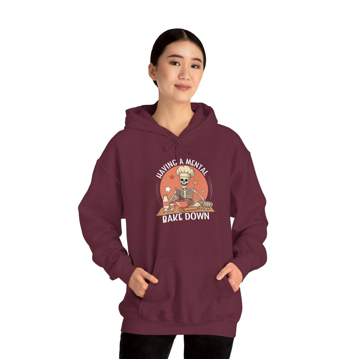 Woman wearing the Having A Mental Bake Down skeleton baker hoodie, hands in pocket