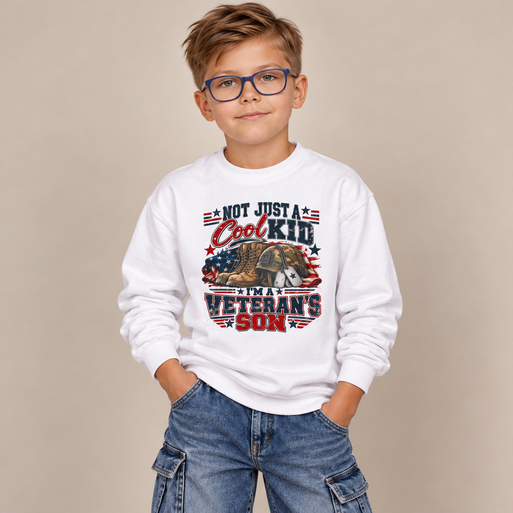 Boy in glasses wearing the White Not Just A Cool Kid I'm A Veteran's Son Youth Sweatshirt